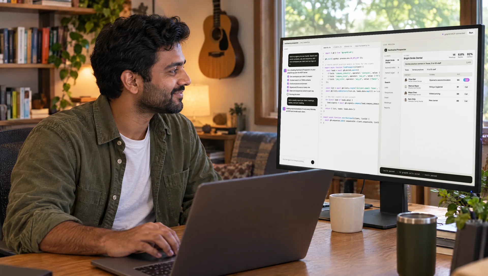 A GTM engineer smiles at his monitor in a home office, the monitor showing an agent chat, graph8 SDK code, and a live preview of the app he is building